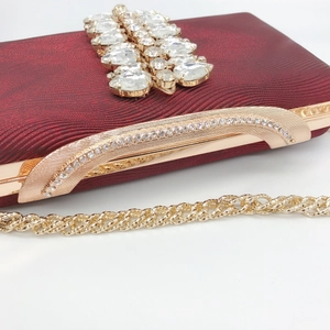 Detail of burgundy evening clutch with rhinestones and gold metal chain strap