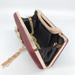 Macro detail of wine red evening bag with crystals, gold tassels and fine chain