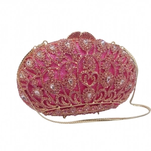Detail of evening clutch bag showing rose red rhinestones and golden snake chain