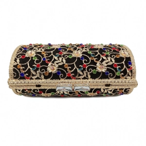 Close-up of hollow metal evening clutch with colorful rhinestones and gold floral patterns