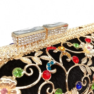 Close-up of gold floral metal cutouts and colorful rhinestones on a black evening clutch