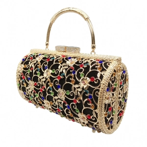 Macro view of a cylindrical gold filigree evening bag with colorful crystals and top handle
