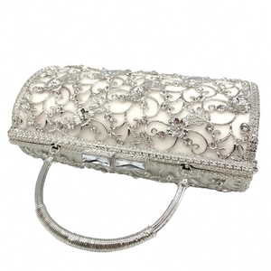 Detailed macro view of hollowed metal evening bag with rhinestones and white satin lining