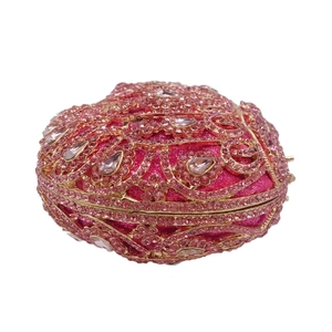 Detailed close-up of pink rhinestones, teardrop gems and golden hollow-out metal clutch bag