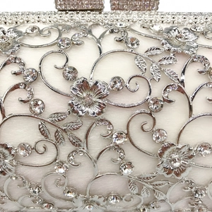 Macro detail of intricate silver floral hollow metalwork with sparkling crystals on evening bag