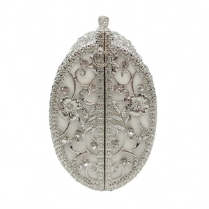 Detailed close-up of hollow metal flowers with hand-set rhinestones on silver clutch bag