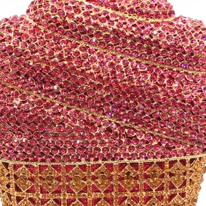 Gros plan d'un sac de soirée avec strass roses et cadre en métal doré ajouré