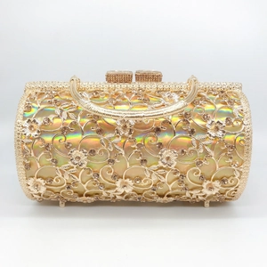 Macro detail of hollowed metal floral texture and rhinestones on luxury gold evening bag
