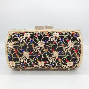 Close-up of golden hollow floral metalwork and colorful rhinestones on a black evening bag