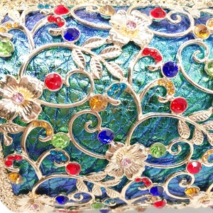 Detail of hollow gold metal floral pattern with multi-colored crystals on evening clutch