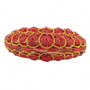 Detailed view of red and yellow crystals on luxury oval clutch bag with gold frame