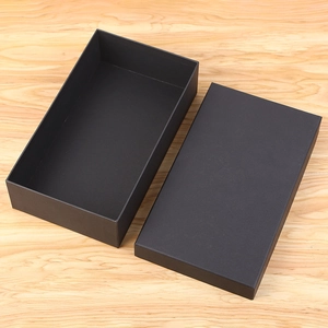 Close-up of matte black gift box packaging on a light wood grain surface for evening bag