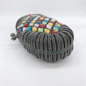 Detail einer Luxus-Clutch mit bunten Strasssteinen und kunstvollem hohlem Metallmuster