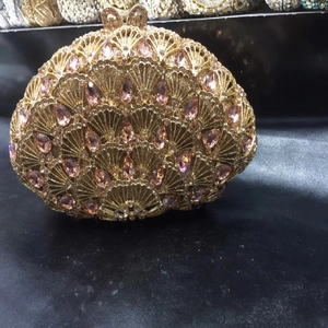 Détail de la pochette de soirée paon en cristal rose avec fermoir nœud et cadre doré