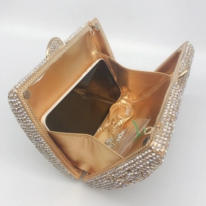 Golden rhinestone evening clutch bag with chain strap, showing interior phone storage space