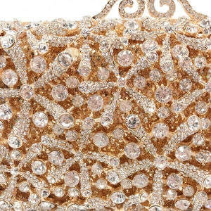 Close-up of golden hollow metal frame with pave-set white crystals on evening bag