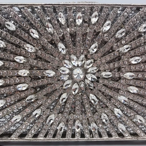 Close-up of intricate silver floral rhinestone patterns on a luxury evening clutch bag