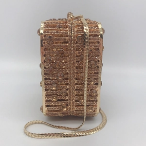 Detail of champagne gold clutch with crystal embellishments and metal stripes