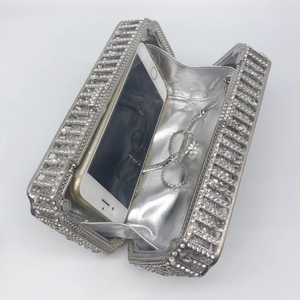 Detail view of silver rhinestone clutch bag showing interior space with phone for scale