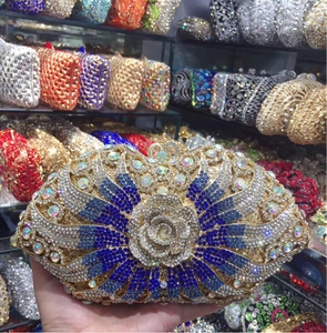 Detail of luxury golden evening clutch with blue rhinestones and 3D metal rose flower