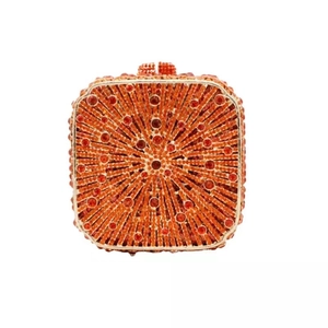 Macro shot of orange evening clutch featuring radial rhinestone inlay and metallic frame