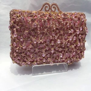 Detail of pink crystal evening bag with golden wavy metal clasp and rhinestone finish