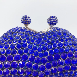 Close-up of double spherical metal clasp with rhinestones on a blue evening clutch bag