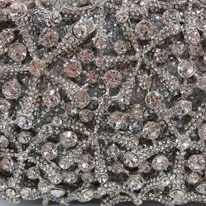 Macro detail of luxury evening bag showing silver metal frame and sparkling rhinestones