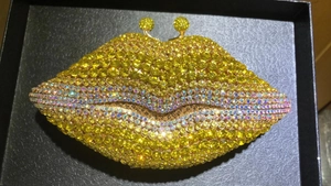 Macro shot of sparkling yellow rhinestone-studded lip evening bag with golden clasp