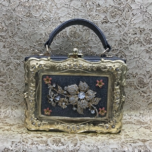 Detailed view of floral crystal embellishments and gold embossed frame on evening clutch