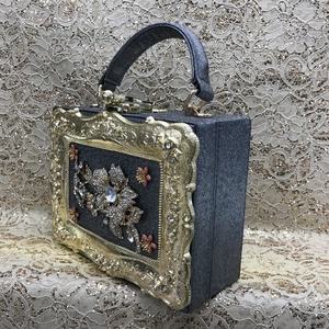 Detail of evening handbag with a gold floral frame and pink floral rhinestone embellishment