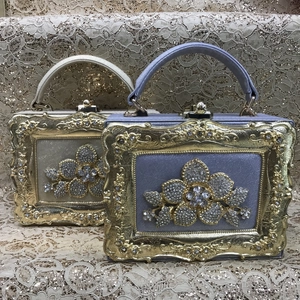 Close-up of luxury boxed evening handbags with gold floral frames and crystal floral clusters
