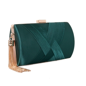 Detail of dark green satin evening clutch with woven pleats and gold tassel chain