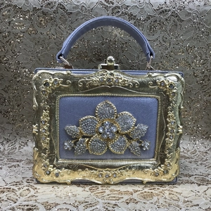 Macro view of purple satin box evening bag with crystal flower and gold ornate frame