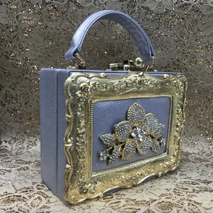 Detail of lavender evening clutch featuring vintage gold frame and crystal flower embellishment