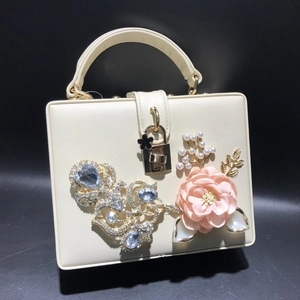 Détail d'un sac boîte crème avec fleurs 3D, perles et strass décoratifs luxueux