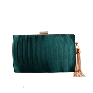 Detailed view of dark green pleated silk evening bag with elegant gold tassel and metal clasp