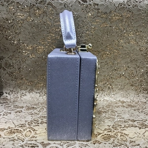 Lilac box clutch bag with gold-tone hardware and embossed side detail macro view