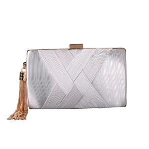 Detail of pearl white woven evening clutch with gold metal fringe and clasp closure