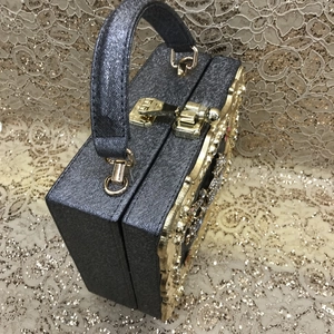 Detailed view of dark grey evening bag with gold lace hollow pattern and rhinestones