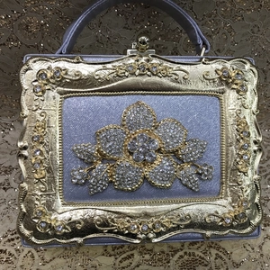 Detail of light purple evening bag with oversized crystal flower and vintage gold frame