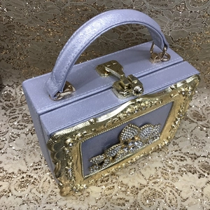 Close-up of lilac box clutch with gold-tone floral relief and sparkling rhinestones