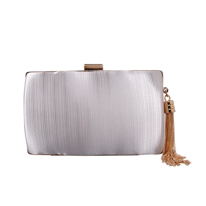 Detail of silver satin evening clutch featuring vertical pleats and a gold tassel charm