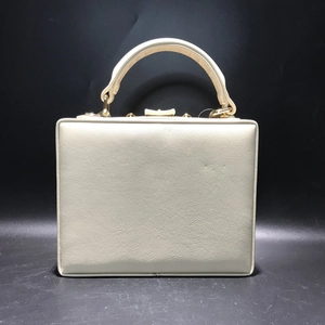 Détail de la pochette rigide blanc crème avec texture cuir grainé et finitions dorées