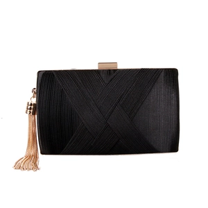 Detail of black silk evening clutch featuring fine texture and golden tassel charm