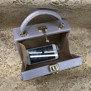 Macro view of purple pearlescent box bag interior with gold hardware showing phone storage