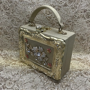 Detail of champagne gold box evening clutch bag with pink crystal flower decorations