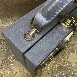 Detail of silver structured evening bag with metallic texture and gold push-lock closure
