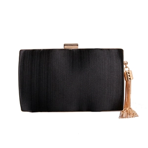 Close-up of black silk evening bag with elegant gold metal frame and long tassel detail