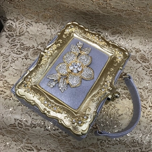 Detail of lilac evening bag with baroque gold floral frame and rhinestone embellishments